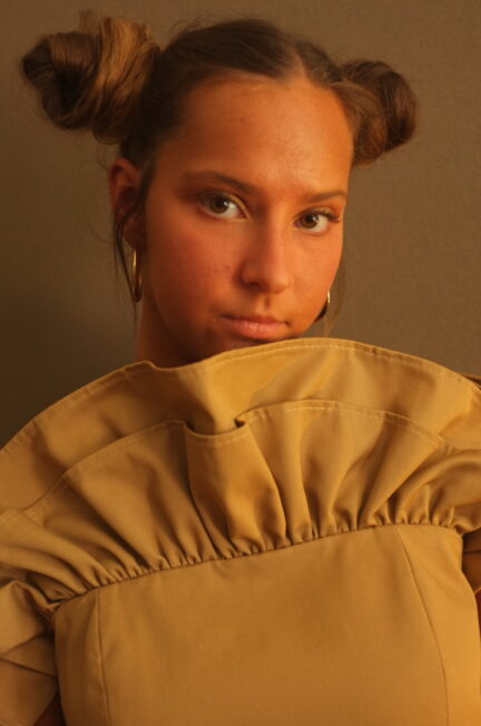 Model draagt een zelfgemaakt beige topje met plooidetail en volumineuze vorm